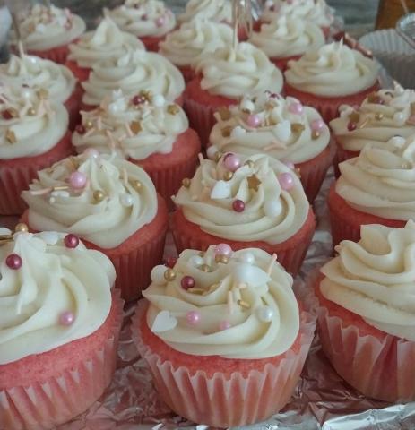 Pink cupcakes with white frosting and sprinkles. 