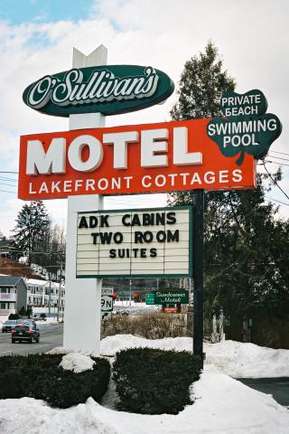 Photograph of green, red, white and black sign for Sullivan's Motel in winter