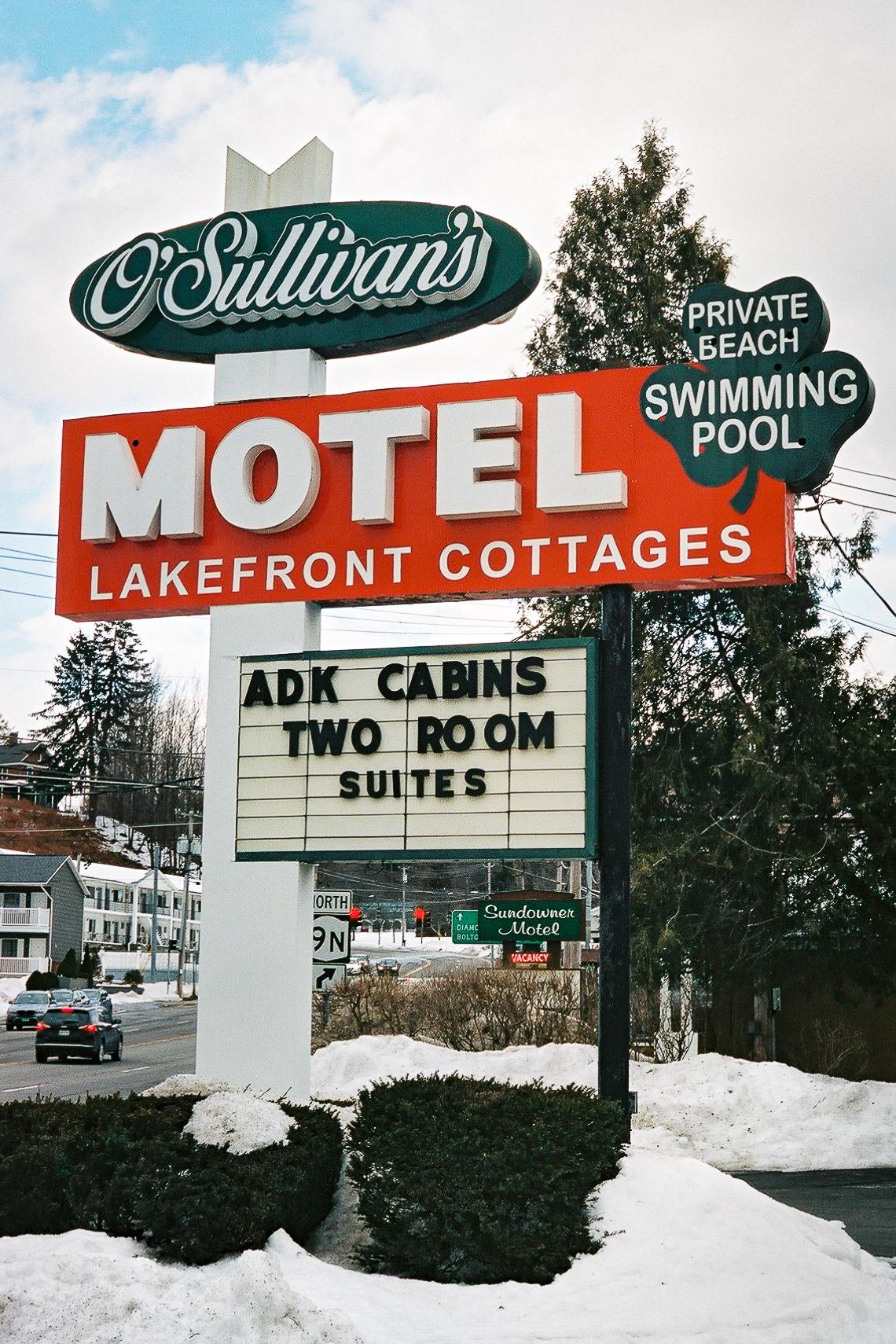 Photograph of green, red, white and black sign for Sullivan's Motel in winter